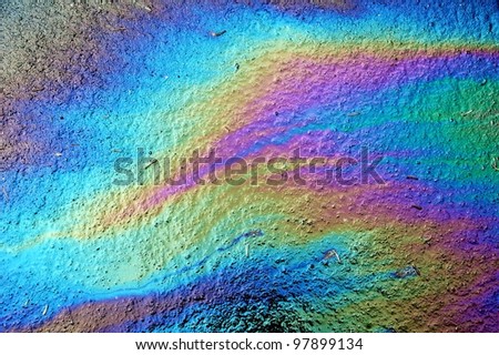 Gasoline that had leaked onto a wet parking lot creates a rainbow oil slick Royalty-Free Stock Photo #97899134