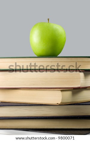 Green apple on books on grey background
