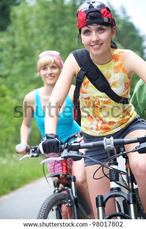 Young pretty women  ride on  bicycle  along road in green park