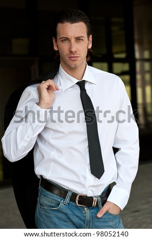 Confident young business man looking at camera. Dark background.
