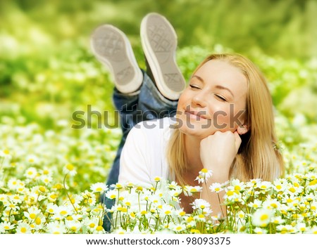 Beautiful woman enjoying daisy field, nice female lying down in the meadow of flowers, pretty girl relaxing outdoor, having fun, happy young lady and spring green nature, harmony and freedom concept Royalty-Free Stock Photo #98093375