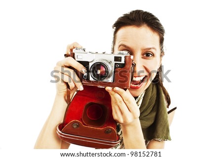 Excited young woman taking a picture with an old camera against white background