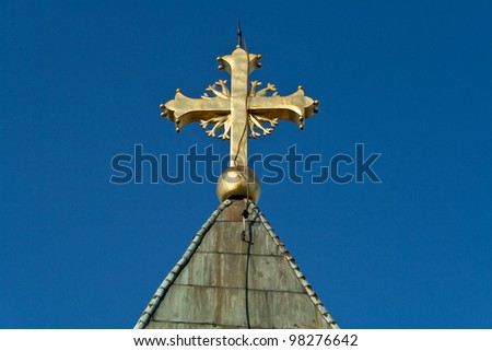 Golden cross on church over blue sky