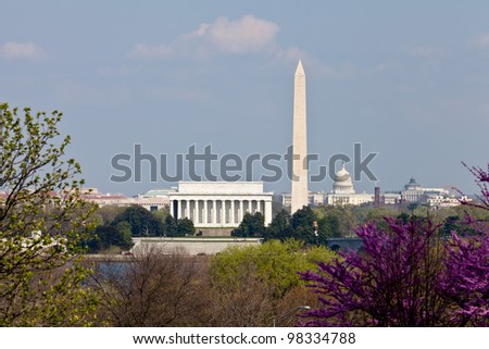 View of Washington DC skyline in late afternoon on a sunny day with Lincoln Memorial, Washington Monument and the Capitol with a blooming redbud