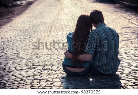 Couple of teenagers sit in street together Royalty-Free Stock Photo #98370575
