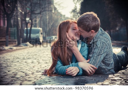 Couple of teenagers lying in street together Royalty-Free Stock Photo #98370596