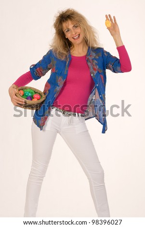 Woman dresses fashionably Easter eggs in the hand, on neutral background in a basket / Woman dresses fashionably Easter eggs in the hand in a basket