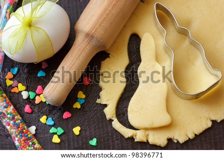 Easter bunny cookies, rolling pin and egg with ribbon on an old wooden table.