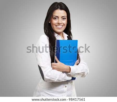young woman smiling and holding a notebook against a grey background