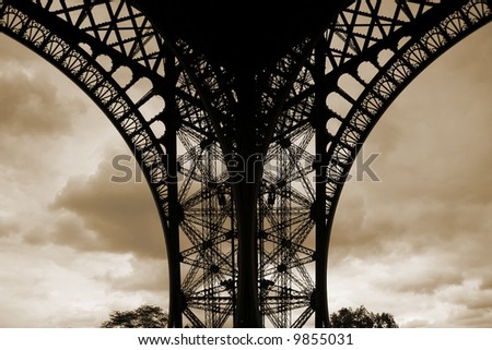 foot of the eiffel tower on sepia cloud background, paris, france