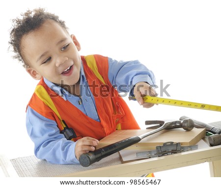 An adorable 2-year-old "construction worker" happily taking measurements.  On a white background.