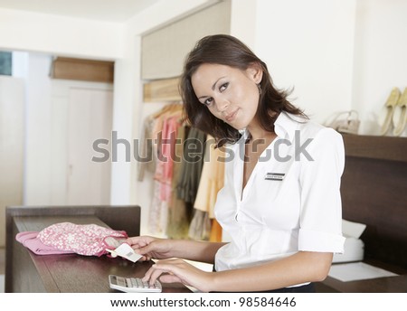 Young store attendant working out her business finances with a calculator,