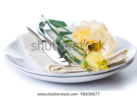 Plate, cutlery and yellow flower on a white background
