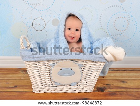 baby boy sitting in basket with blanket on head