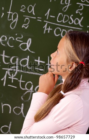 Schoolgirl on the background of a blackboard