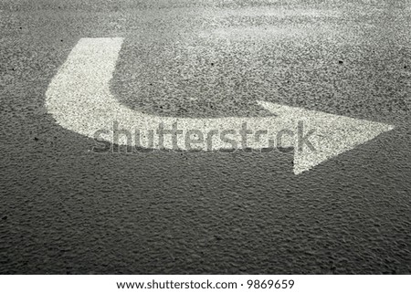 White arrow on wet grey asphalt
