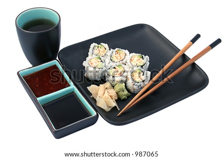 A sushi roll dinner complete with tea and sauces for dipping.  Isolated.
