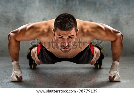 Young athletic fighter doing push ups in grunge environment./Push-up Royalty-Free Stock Photo #98779139