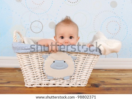 handsome baby boy playfully peeking out of wicker basket