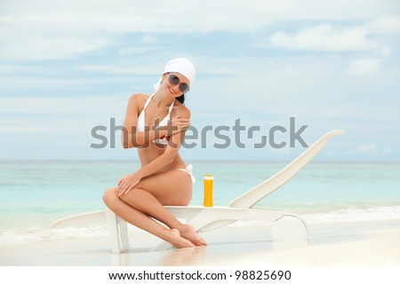 Young woman with sun-protection cream on the beach