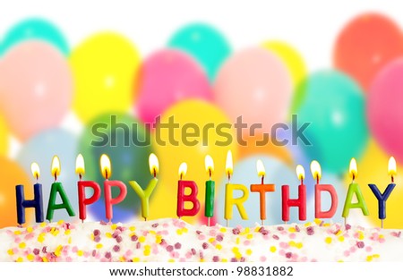Happy birthday lit candles on colorful balloons background