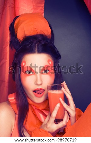 Young woman in orange cloth with glass of carrot juice