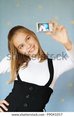 Beautiful blue-eyed girl-teenager photographed with camera itself, on blue background.