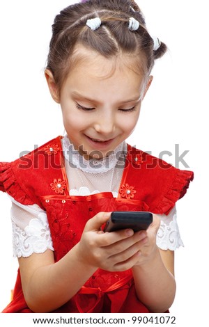 Little smiling girl in red dress reading sms on your cell phone, isolated on white background.