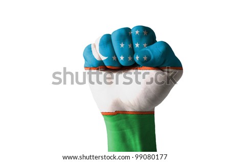 Low key picture of a fist painted in colors of uzbekistan flag