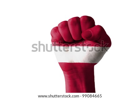 Low key picture of a fist painted in colors of latvia flag