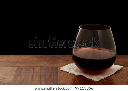 stemless glass of red wine on a bar top isolated on a black background