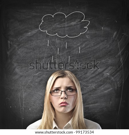 Disappointed young businessman with raincloud drawn over her on a blackboard in the background