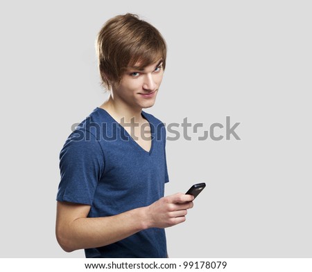 Portrait of handsome young man sending text messages with is mobile phone, over a gray background