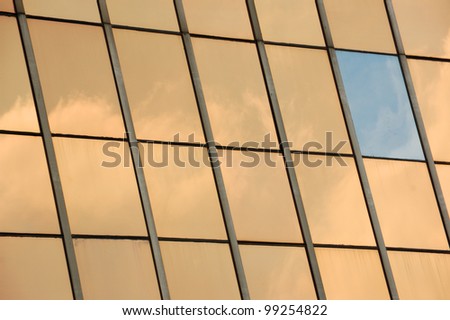 Sky reflected on glass facade panel of a modern building. Abstract background.
