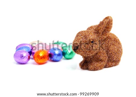 Brown easter bunny and colorful chocolate eggs over white background