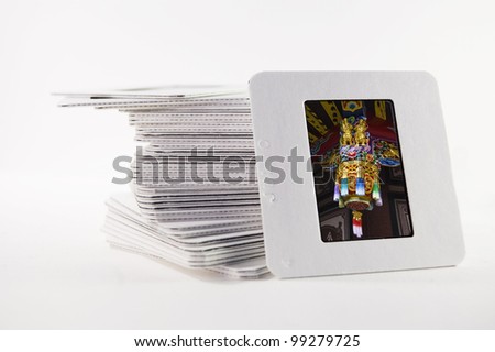 A pile of old slide photographs, with a photograph of a Chinese temple decoration
