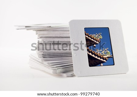 A pile of old slide photographs, with a photograph of a chinese temple roof