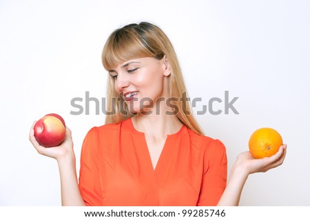 young beautiful blonde girl choosing between apple and orange