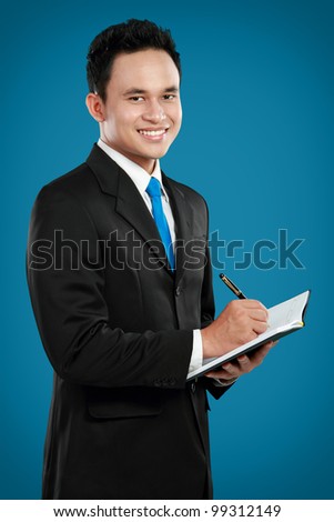Portrait of a handsome young business man with pen writing on binder clip