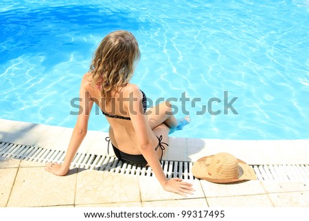 Woman in bikini sitting by the swimming pool