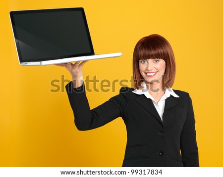funny portrait of a beautiful, young businesswoman, holding a laptop as a tray, smiling, on yellow background
