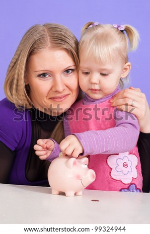 Pretty Caucasian mum with her daughter play with the piggy bank on a light background