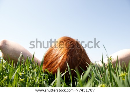 Red haired woman laying in grass looking up Royalty-Free Stock Photo #99431789
