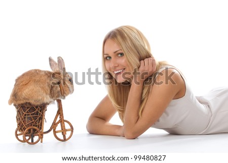 Photo of cute brown rabbit riding bike to young woman lying on floor