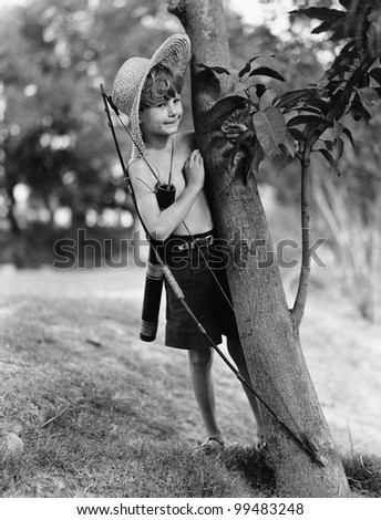 Boy behind tree with bow and arrow Royalty-Free Stock Photo #99483248