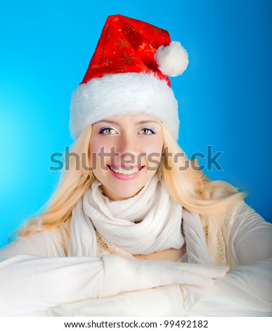 smiling beautiful blonde girl in a santa hat on a blue background