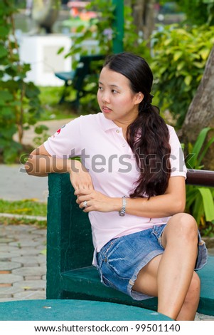 Distracted Asian woman on bench in park