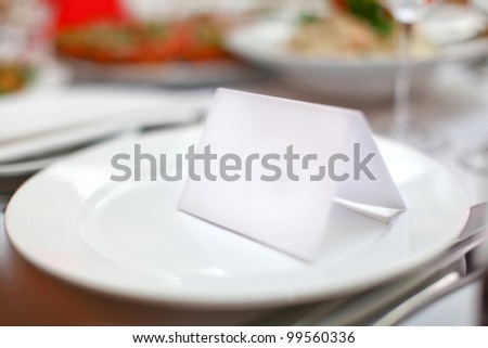 Empty classic white plate in a restaurant with a blank card and copyspace for example guest names.