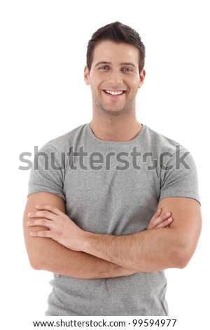 Casual portrait of happy university student guy standing with arms folded, laughing.