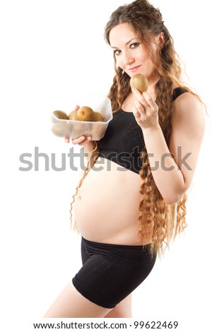 Young  pregnant woman in sports wear with  kiwi on white background. Diet and health concept